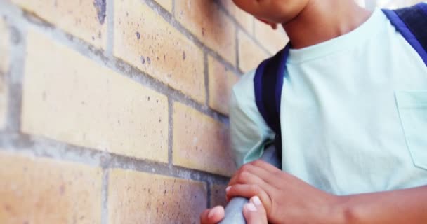 Colegial apoyado en la pared en el pasillo — Vídeos de Stock