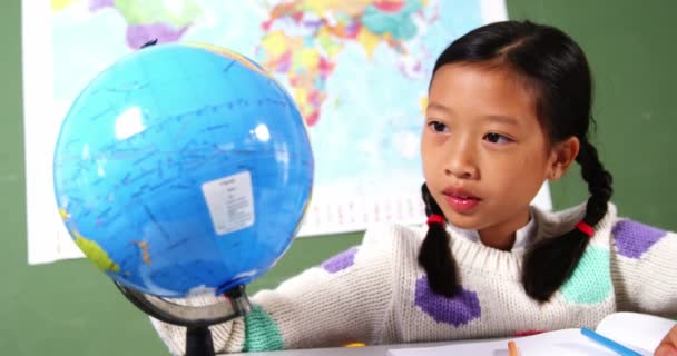 Школьница смотрит на глобус в классе — стоковое видео