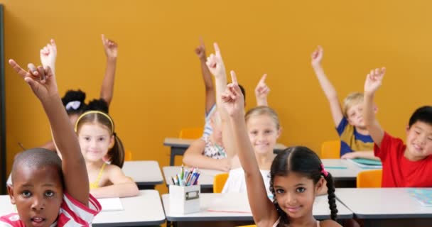 Crianças da escola levantando as mãos na sala de aula — Vídeo de Stock
