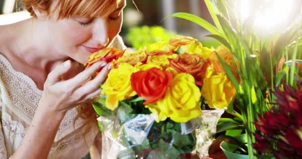 Hermosa florista femenina oliendo rosa — Vídeos de Stock