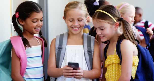 Niños de la escuela usando el teléfono móvil en el pasillo — Vídeo de stock