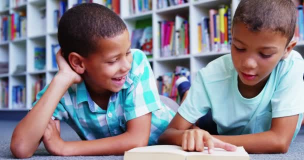 Schüler liegen auf dem Boden und lesen Buch — Stockvideo