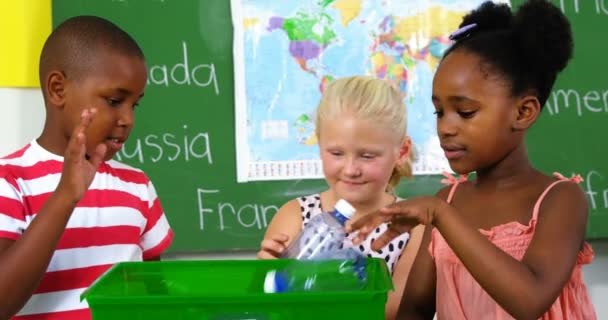 Enfants mettant la bouteille de déchets sur la boîte de logo de recyclage — Video