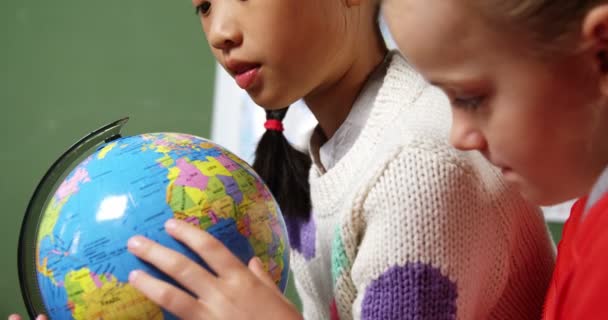 Niños de la escuela mirando el globo en el aula — Vídeo de stock