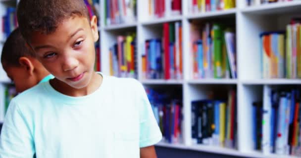 Школьник улыбается в библиотеке в школе — стоковое видео