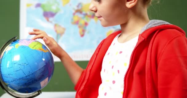 Colegiala mirando globo en el aula — Vídeo de stock