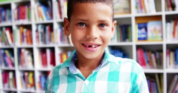 Colegial sonriendo en la biblioteca en la escuela — Vídeo de stock