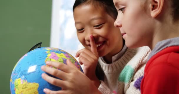 Miúdos da escola a olhar para o globo em sala de aula — Vídeo de Stock