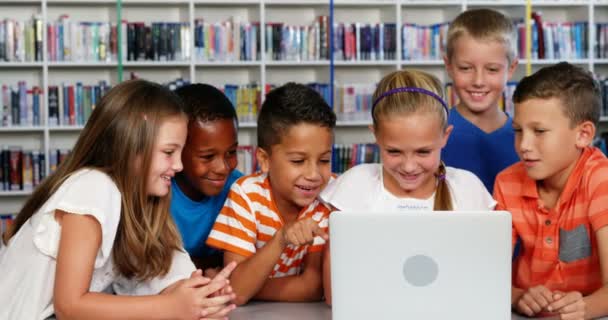Los niños de la escuela usando portátil en la biblioteca — Vídeo de stock