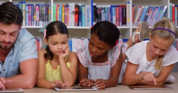 Bambini e insegnanti che utilizzano tablet digitale in biblioteca — Video Stock