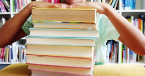 Lachende jongen leunend op stapel boeken — Stockvideo