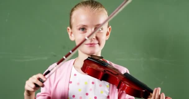 Colegiala sosteniendo violín en el aula en la escuela — Vídeos de Stock