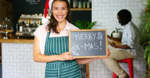 Servitrisen stående med merry x mas styrelse — Stockvideo