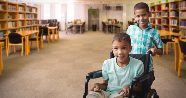 Мальчик толкает друга на инвалидное кресло — стоковое фото