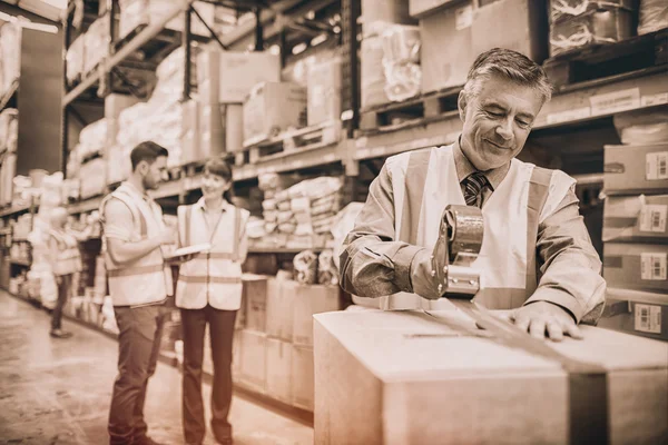 Warehouse worker sealing cardboard boxes — Stock Photo, Image