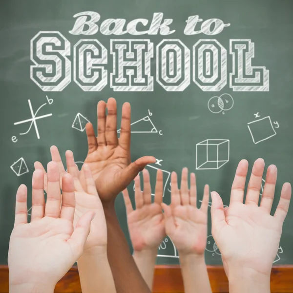 Hands raising in air against blackboard — Stock Photo, Image