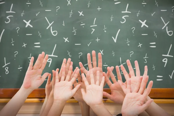 hands raising in air against blackboard