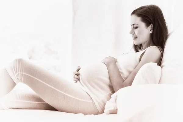 Šťastné těhotná žena sedí na pohovce — Stock fotografie