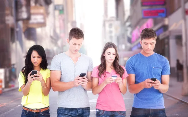 Quattro persone in piedi e sms sui telefoni — Foto Stock