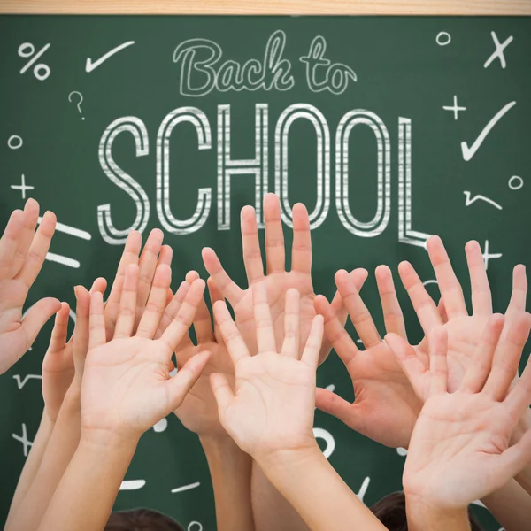 Hands raising in air against blackboard — Stock Photo, Image