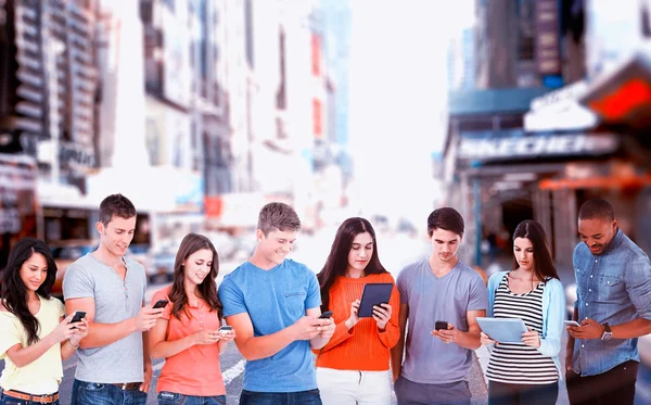 Друзья, стоящие и использующие мобильные устройства — стоковое фото
