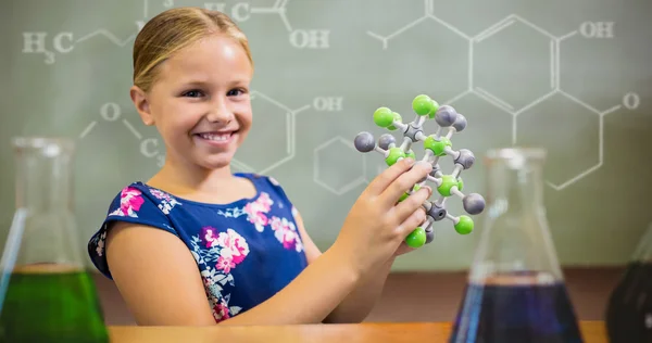 Niña sonriendo mientras sostiene la estructura molecular —  Fotos de Stock