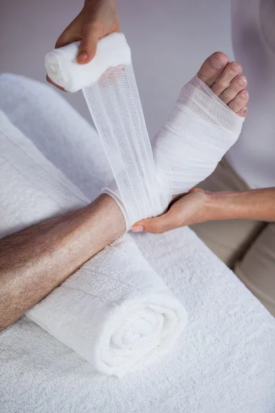 Fyzioterapeut, nasadil zraněné nohy pacienta obvaz — Stock fotografie