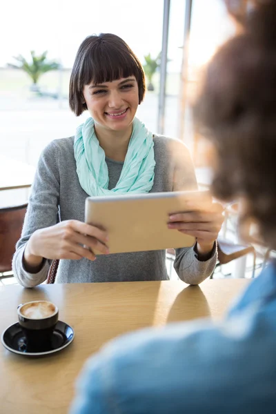 Kvinna med digital tablett med kopp kaffe på bordet — Stockfoto