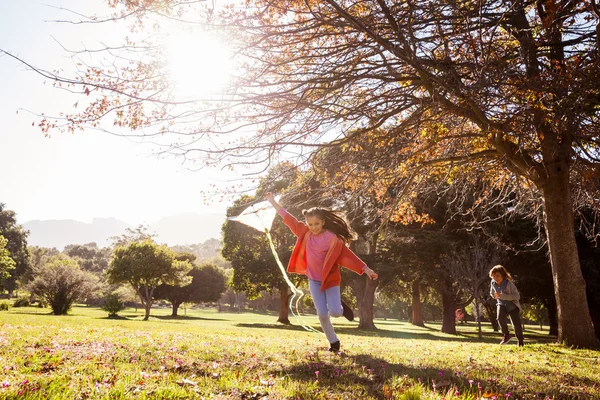 Chica sosteniendo cometa mientras se ejecuta en el parque — Foto de Stock