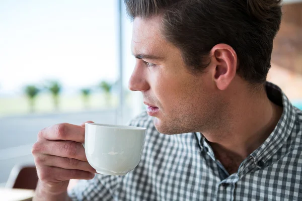 Un uomo premuroso che guarda fuori dalla finestra mentre prende un caffè — Foto Stock