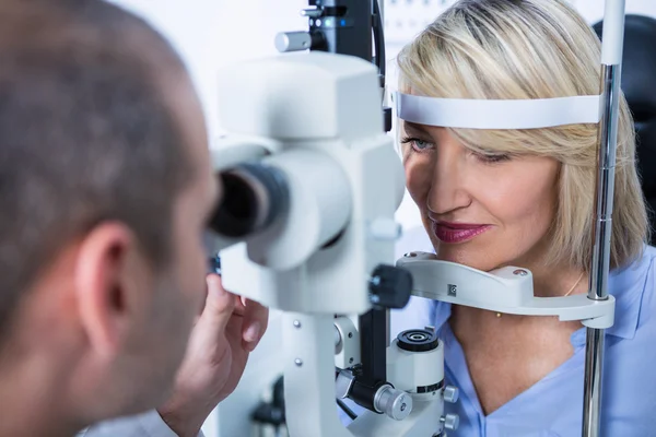 Optiker undersöker kvinnlig patient på spaltlampan — Stockfoto