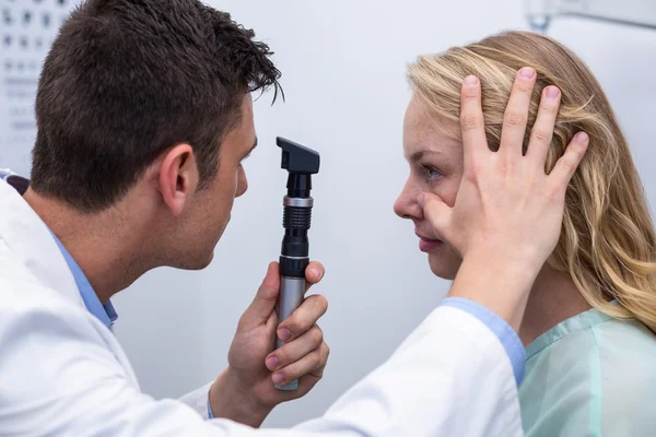 Optiker undersökande kvinnlig patient genom oftalmoskop — Stockfoto