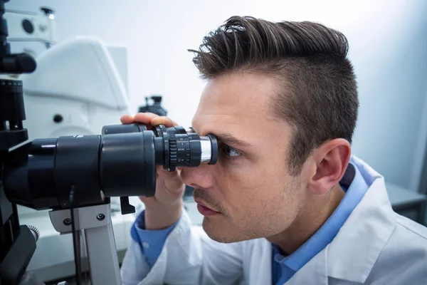 Optometrist looking through biomicroscope — Stock Photo, Image