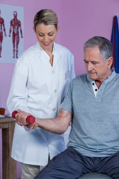 Fyzioterapeut, pomáhat starší muž zvednout činka — Stock fotografie
