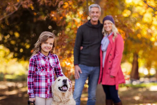 Дівчина з собакою, поки батьки стоять у парку — стокове фото