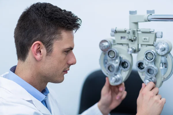 Optometrista atento ajustando phoropter — Fotografia de Stock