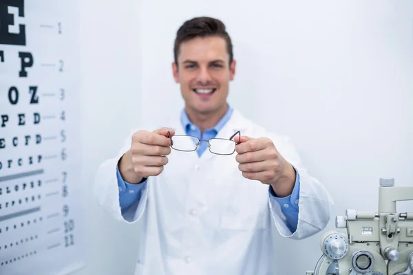 Улыбающийся оптометрист держит очки — стоковое фото