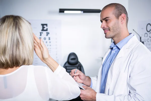 Optometrista masculino que toma la prueba ocular del paciente femenino — Foto de Stock