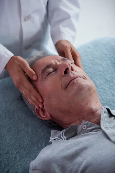 Hombre mayor recibiendo masaje de cabeza de fisioterapeuta — Foto de Stock