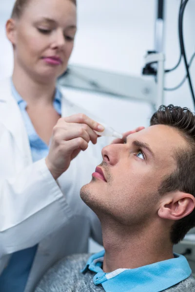 Optometrista femenina colocando colirio en los ojos del paciente —  Fotos de Stock