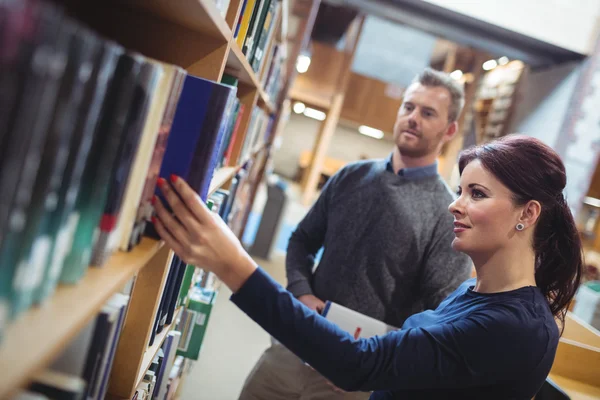 Volwassen student verwijderen van boek van de plank — Stockfoto