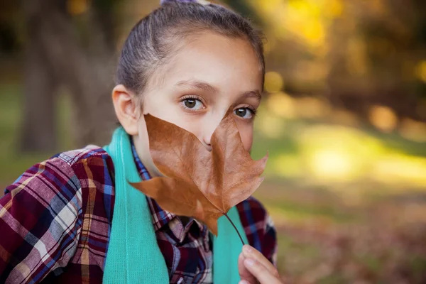 Mädchen versteckt Mund mit Herbstblatt — Stockfoto