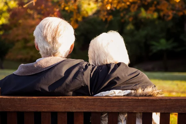 Senior paar omarmen op een bankje — Stockfoto