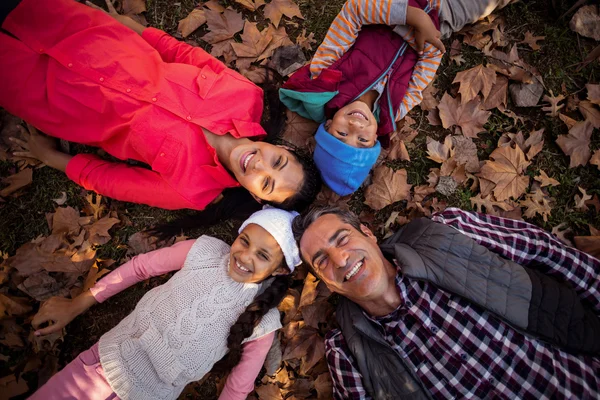 Família formando aconchego enquanto deitado no campo — Fotografia de Stock