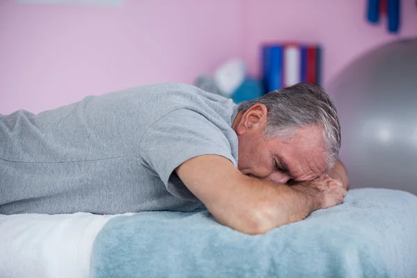 Hombre mayor acostado en una cama de masaje — Foto de Stock