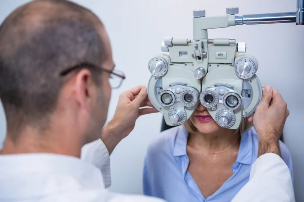 Optometrist examencommissie vrouwelijke patiënt op phoropter — Stockfoto