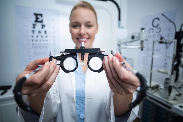 Sonriente optometrista femenina sosteniendo messbrille — Foto de Stock