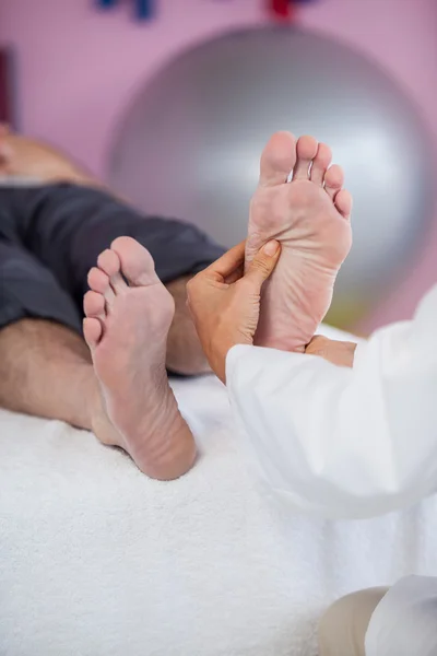 Hombre mayor recibiendo masaje de pies de fisioterapeuta — Foto de Stock