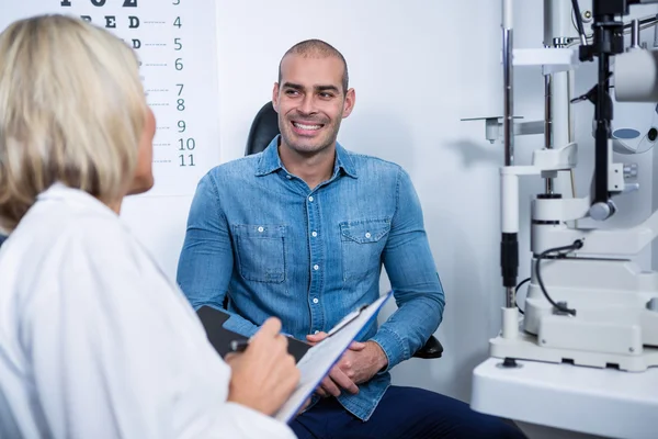 Optométriste féminine parlant à un patient masculin — Photo