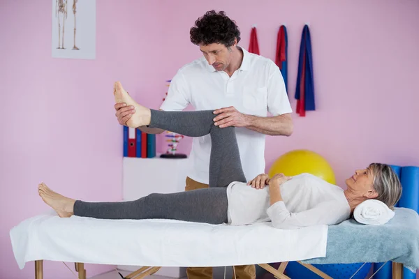 Fisioterapeuta dando massagem nas pernas para uma mulher idosa — Fotografia de Stock